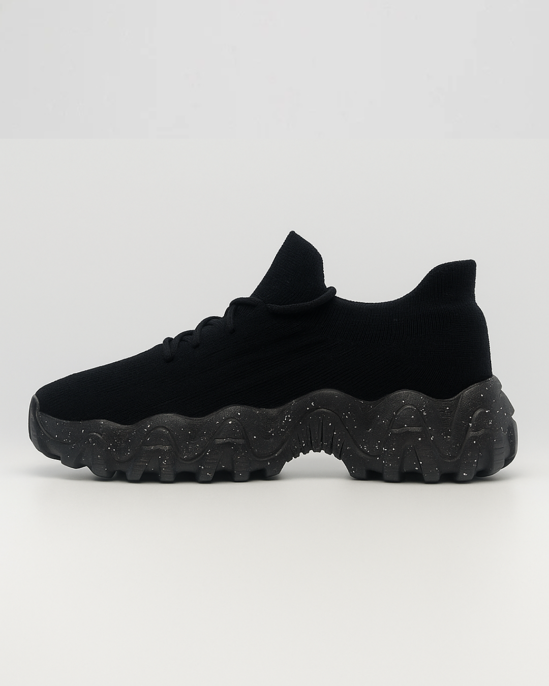 Side view of the right black OrthoEase Luxe sneaker with breathable knit and orthopedic sole.