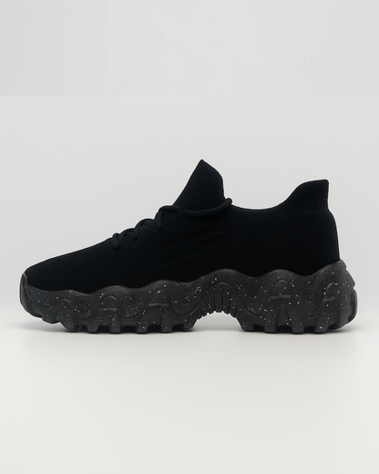 Side view of the right black OrthoEase Luxe sneaker with breathable knit and orthopedic sole.