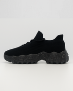 Side view of the right black OrthoEase Luxe sneaker with breathable knit and orthopedic sole.